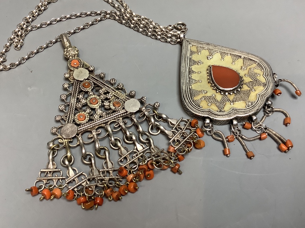 Two shaped Afghan? white metal or parcel gilt white metal, coral bead set pendants, one on a white metal chain